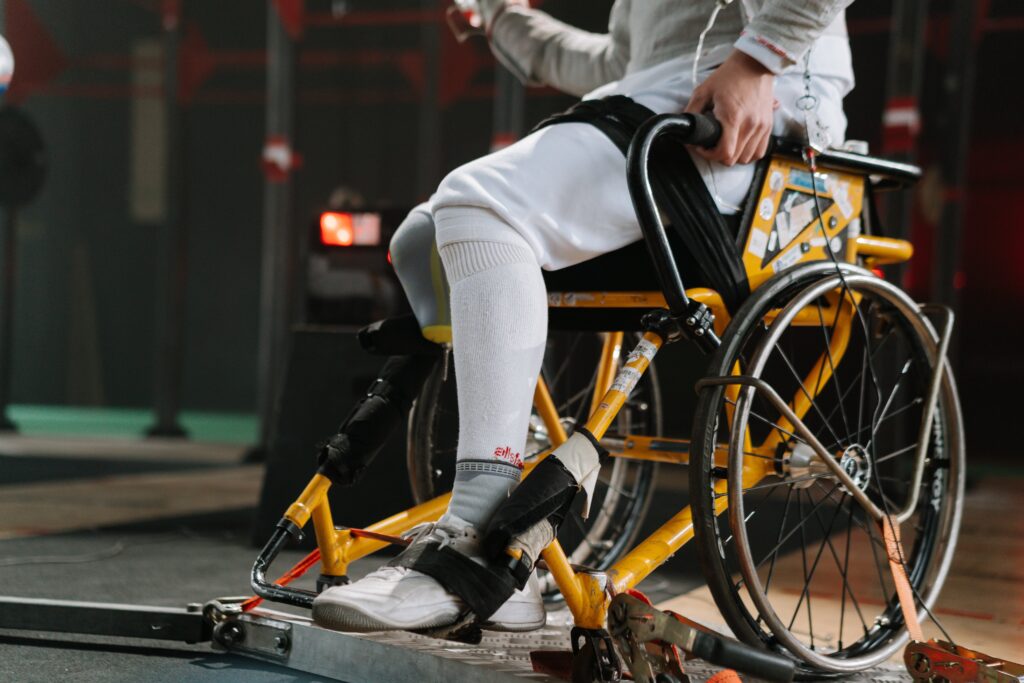 Focused athlete in wheelchair fencing gear, showcasing strength and determination.